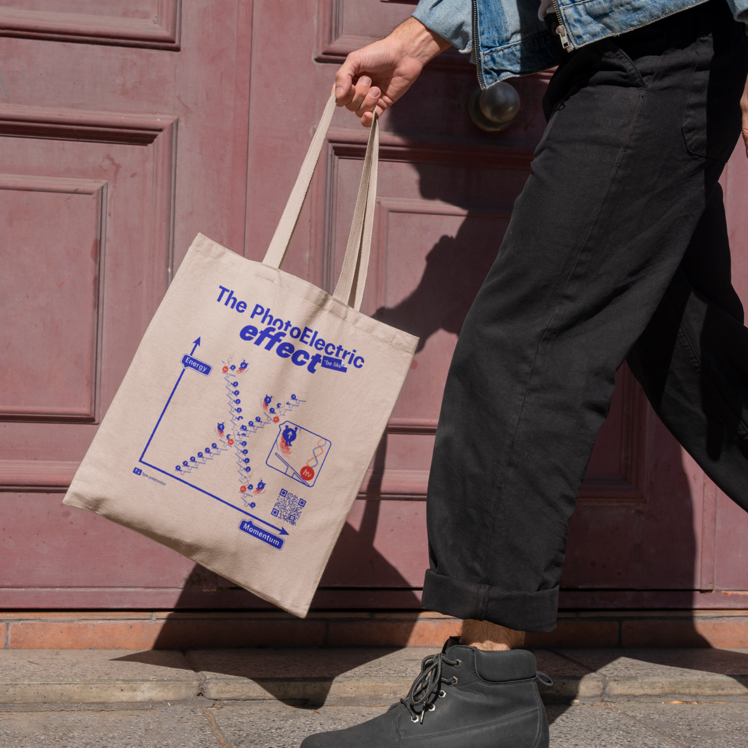 White tote bag with the photoelectric effect, quantum physics-inspired accessory, red door in street background