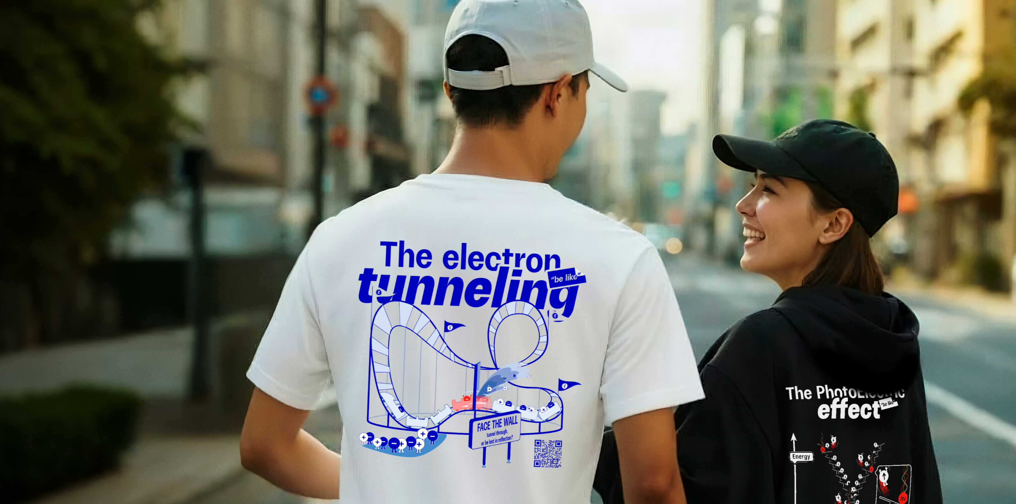 Two people on a street, one wearing a white t-shirt with original quantum physocs electron tunneling design and the other in a black hoodie sh.wing the photoelectric effect.