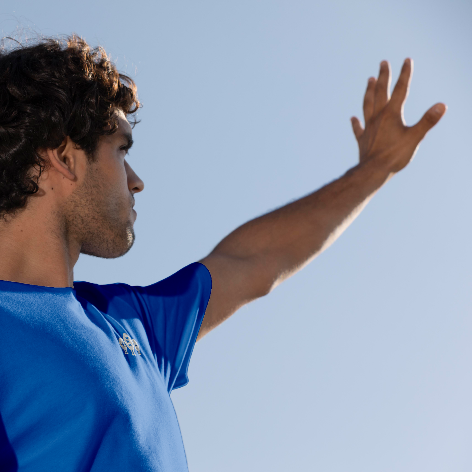 Man wearing a bluet-shirt with quantum tryon embrodery on a blue background zoomed